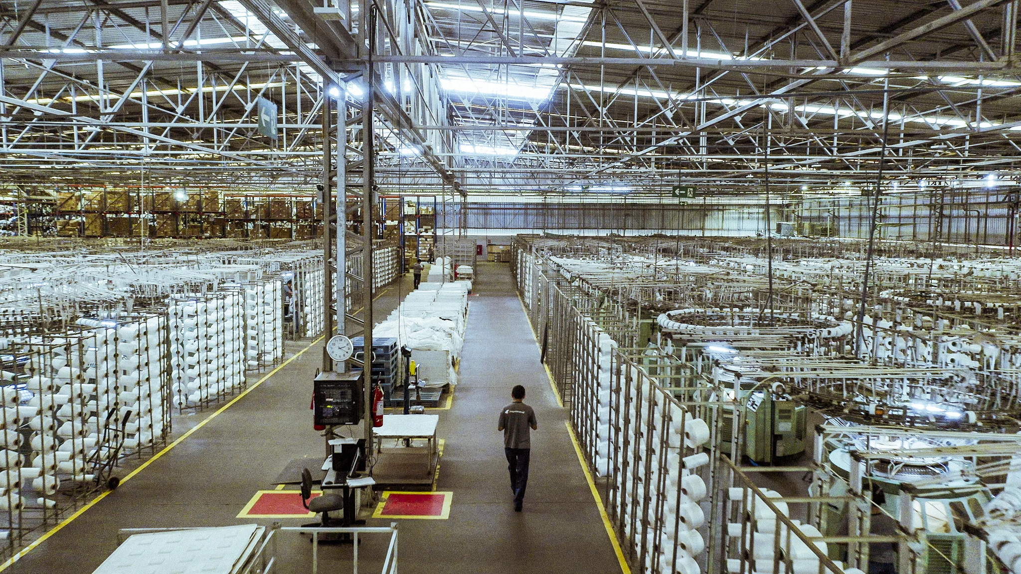 Interior da fábrica têxtil com maquinário de produção.