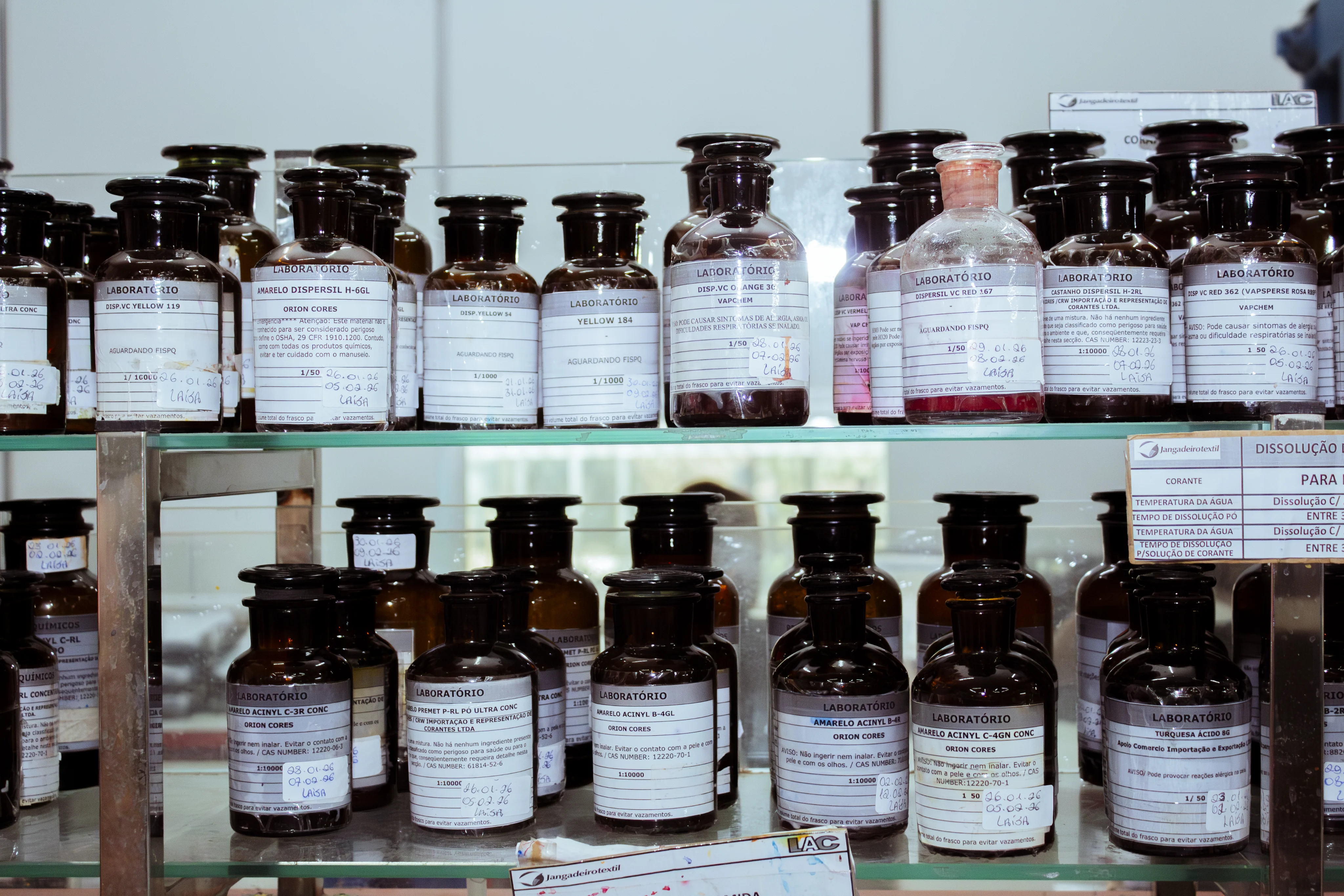 Frascos de produtos químicos organizados em prateleiras.